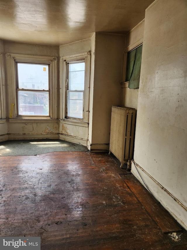 spare room with radiator and dark hardwood / wood-style floors