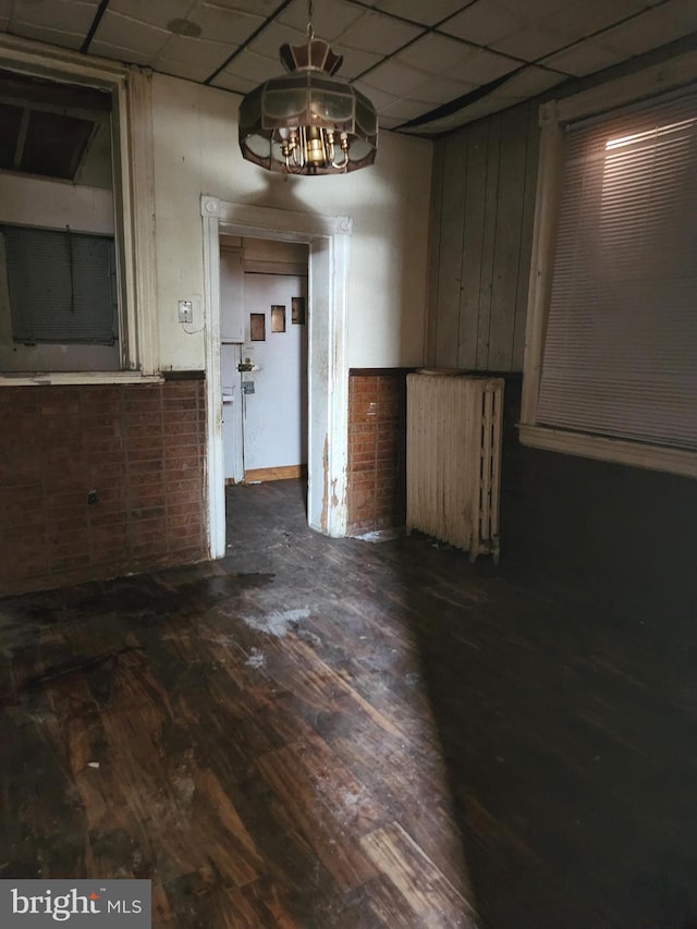 spare room featuring dark hardwood / wood-style floors and a paneled ceiling