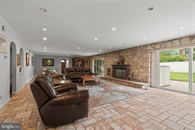 living room with crown molding and a stone fireplace