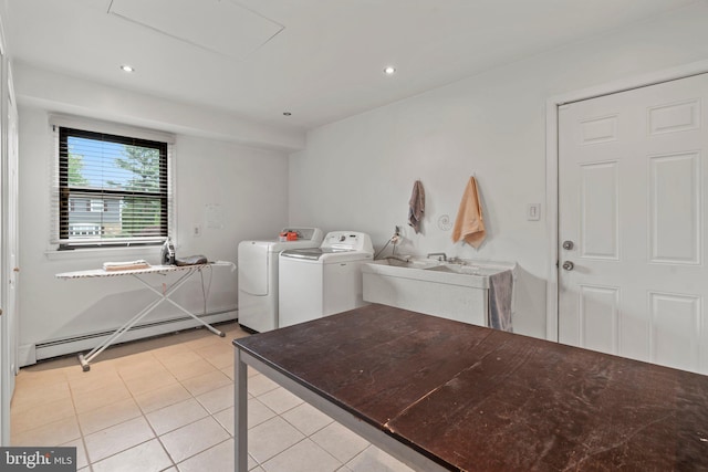 clothes washing area featuring light tile patterned flooring, sink, washing machine and dryer, and a baseboard heating unit