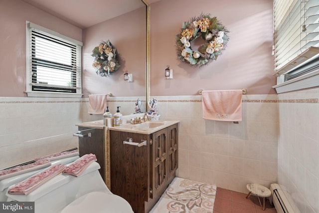 bathroom with baseboard heating, tile walls, vanity, tile patterned floors, and toilet