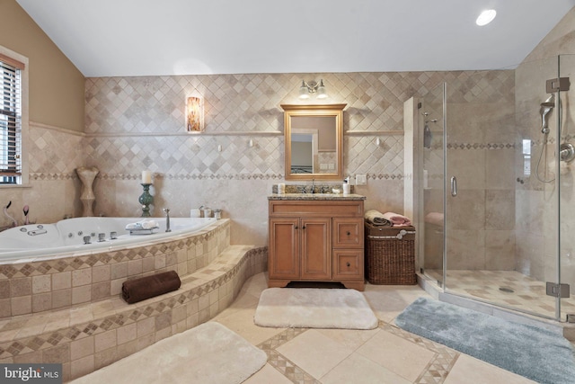 bathroom featuring plus walk in shower, lofted ceiling, tile walls, tile patterned flooring, and vanity