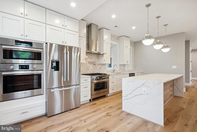 kitchen featuring stainless steel appliances, wall chimney range hood, backsplash, and light wood-type flooring