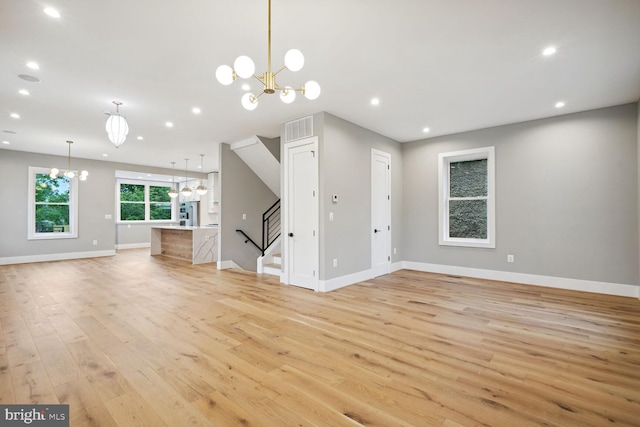 unfurnished living room with light wood-type flooring and a chandelier