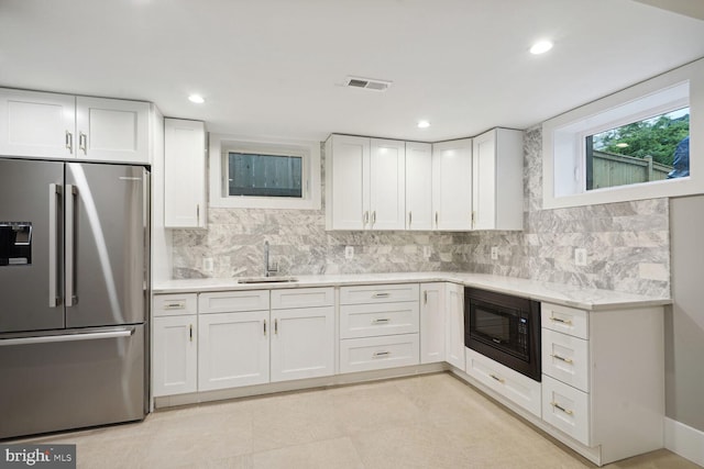 kitchen featuring sink, stainless steel fridge, backsplash, and black microwave