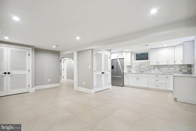 kitchen with tasteful backsplash, light tile flooring, high end fridge, and white cabinetry