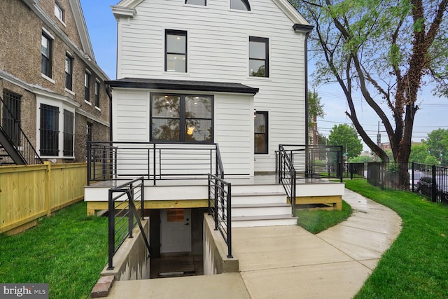 back of house featuring a deck and a lawn