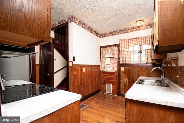 kitchen featuring sink, stove, a textured ceiling, and light wood-type flooring