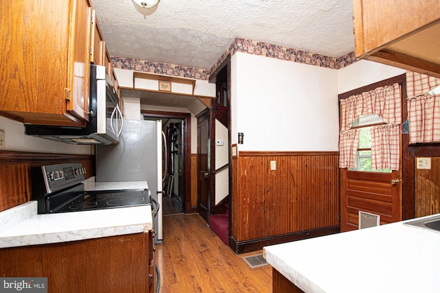 kitchen featuring appliances with stainless steel finishes, a textured ceiling, and light hardwood / wood-style flooring