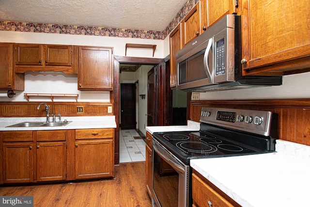 kitchen featuring light tile floors, appliances with stainless steel finishes, sink, and a textured ceiling