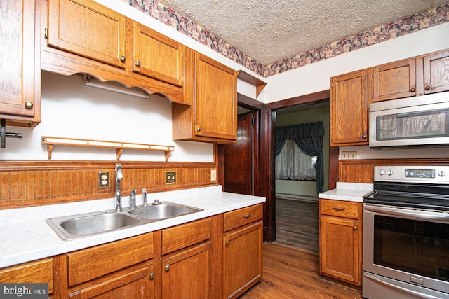 kitchen featuring stainless steel appliances, dark wood-type flooring, sink, and a textured ceiling