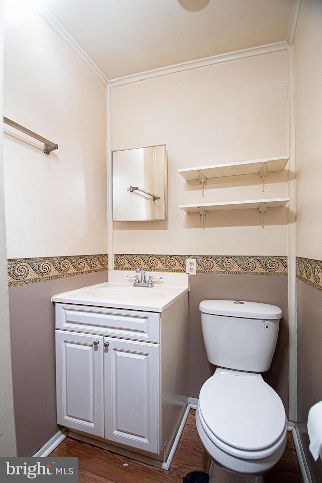 bathroom featuring crown molding, hardwood / wood-style floors, toilet, and vanity with extensive cabinet space