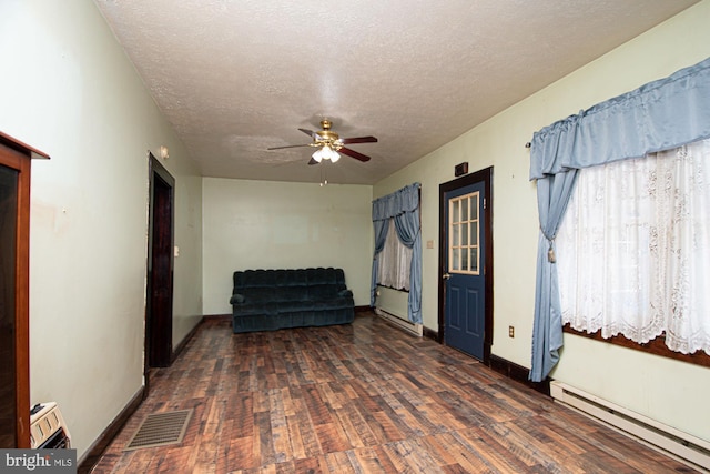 unfurnished room featuring ceiling fan, a textured ceiling, baseboard heating, and dark wood-type flooring