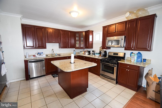 kitchen featuring light stone counters, stainless steel appliances, a center island, ornamental molding, and sink