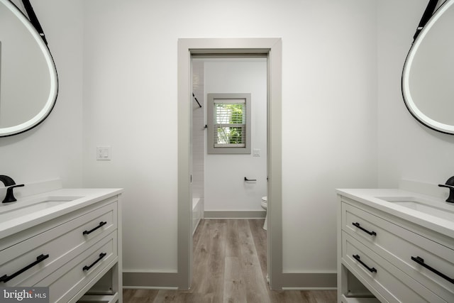 full bathroom with washtub / shower combination, wood-type flooring, oversized vanity, and toilet