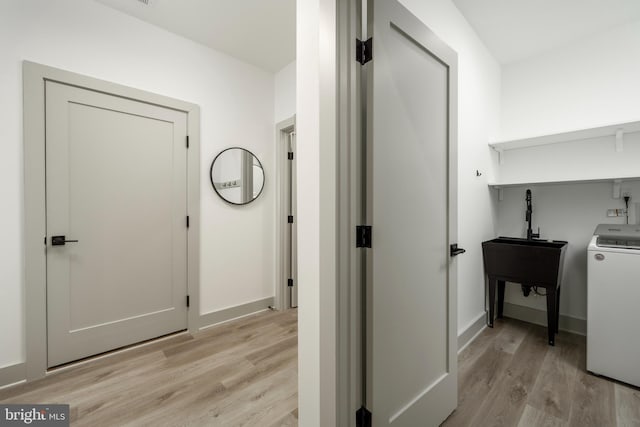 corridor featuring sink, light hardwood / wood-style floors, and washer / clothes dryer