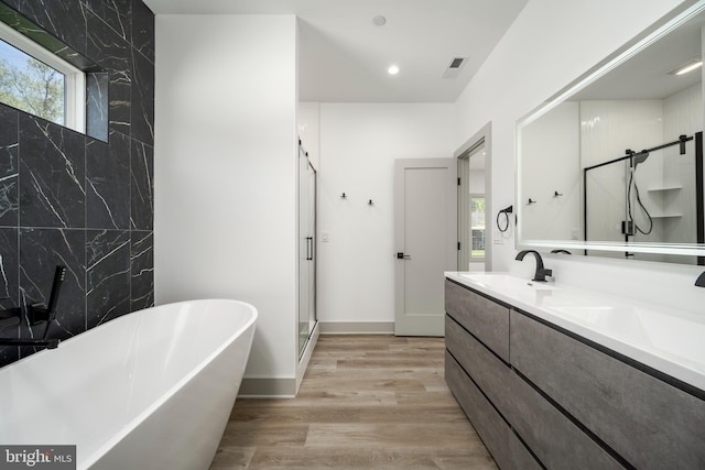 bathroom with shower with separate bathtub, wood-type flooring, and large vanity