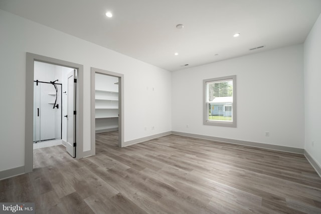 unfurnished bedroom with a closet, hardwood / wood-style floors, and a spacious closet