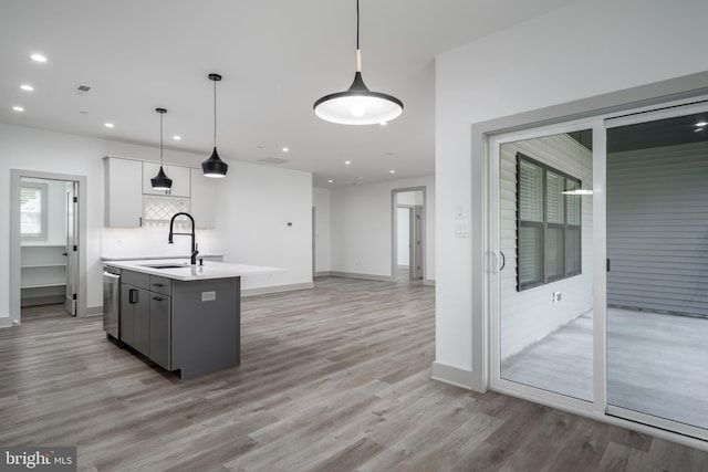 kitchen featuring an island with sink, white cabinetry, sink, and light hardwood / wood-style floors