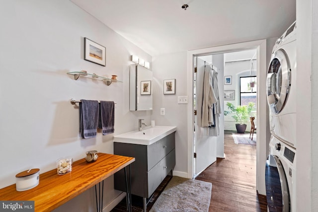 bathroom with wood-type flooring, vanity, and stacked washing maching and dryer