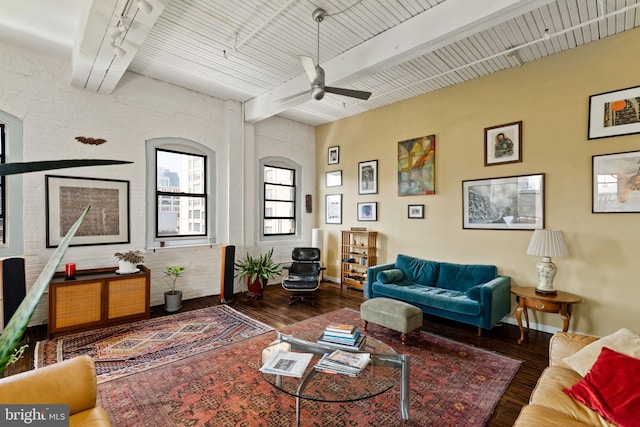 living room with ceiling fan, beam ceiling, wood-type flooring, and brick wall