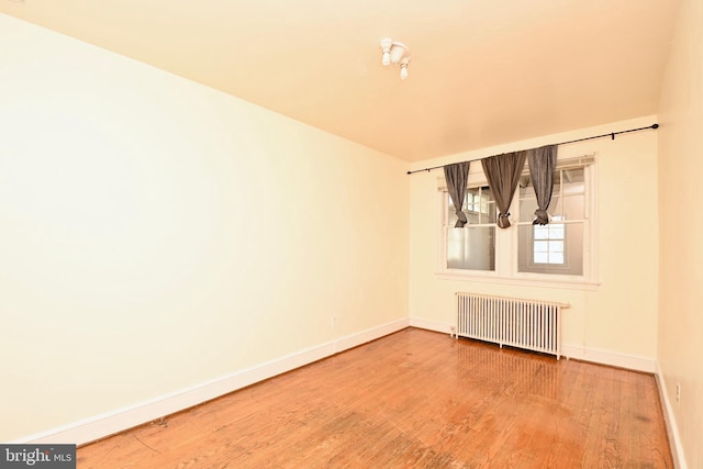 unfurnished room with hardwood / wood-style flooring and radiator heating unit