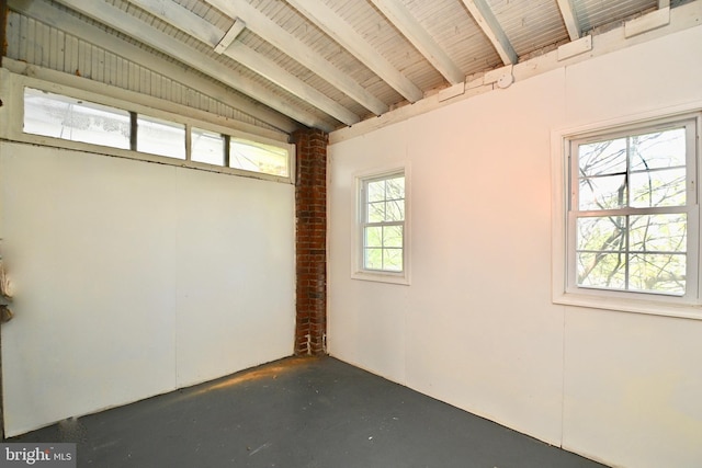 spare room featuring a wealth of natural light, brick wall, wood ceiling, and vaulted ceiling with beams