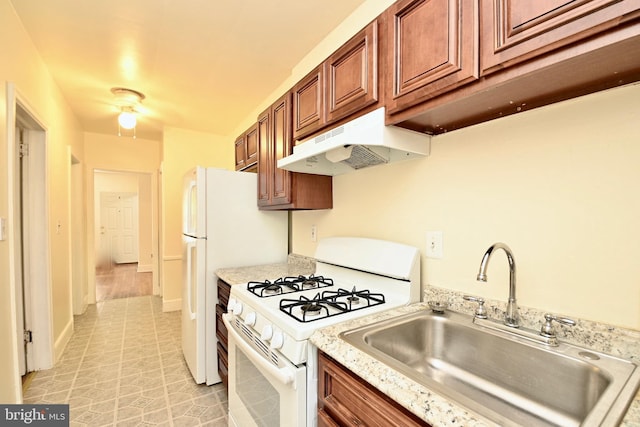 kitchen with gas range gas stove, light stone counters, light tile flooring, and sink