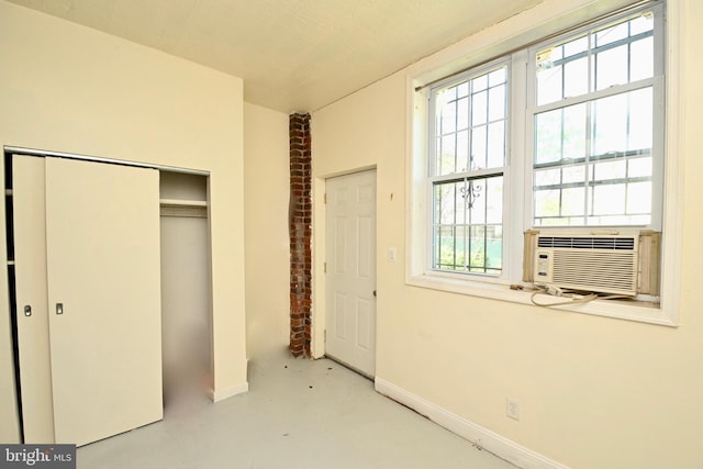 unfurnished bedroom with brick wall, concrete floors, and a closet