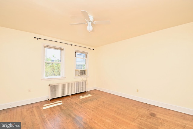 empty room with ceiling fan, hardwood / wood-style floors, and radiator