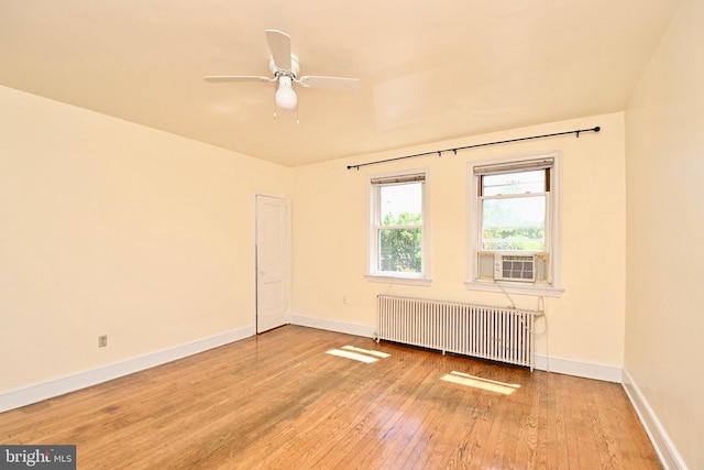 empty room featuring ceiling fan, radiator heating unit, and hardwood / wood-style floors