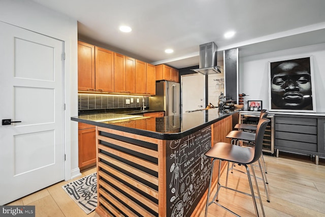 kitchen featuring light hardwood / wood-style flooring, backsplash, a breakfast bar area, high end refrigerator, and range hood