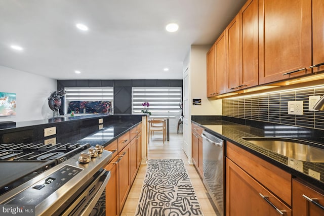 kitchen featuring backsplash, dark stone counters, light hardwood / wood-style flooring, and stainless steel appliances