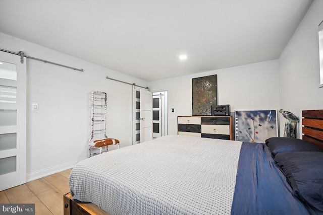 bedroom with wood-type flooring and a barn door