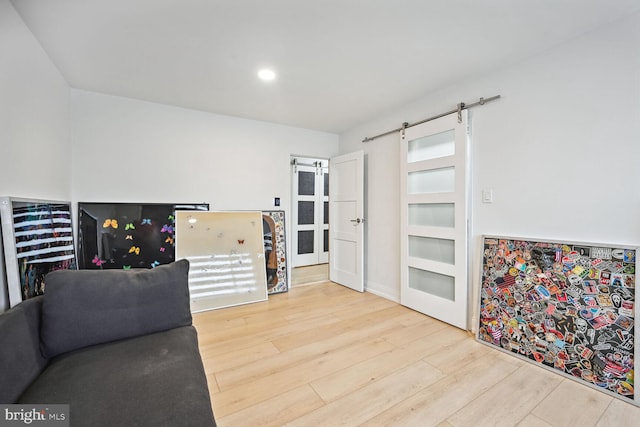 sitting room with a barn door, light hardwood / wood-style flooring, and beverage cooler