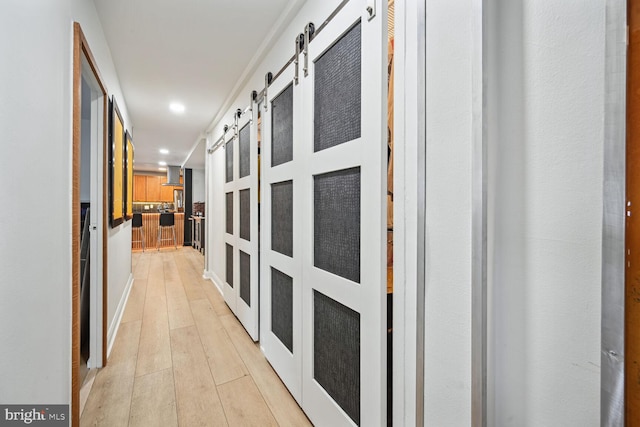 corridor with a barn door and light wood-type flooring