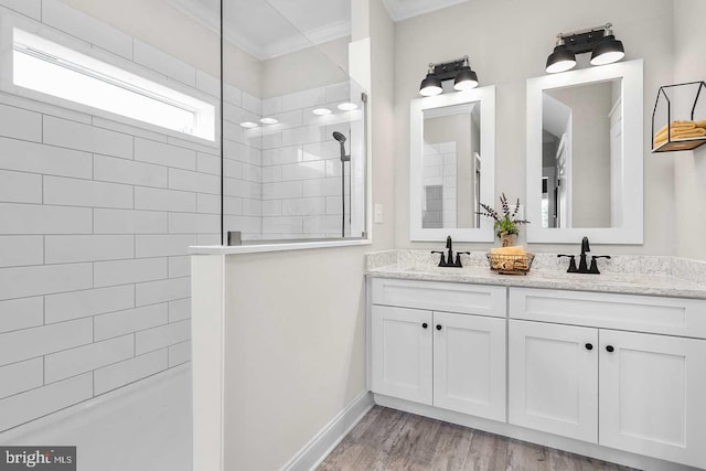 bathroom with wood-type flooring, vanity with extensive cabinet space, ornamental molding, and dual sinks