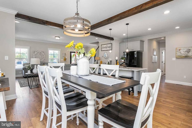 dining area with wood-type flooring, beam ceiling, and crown molding