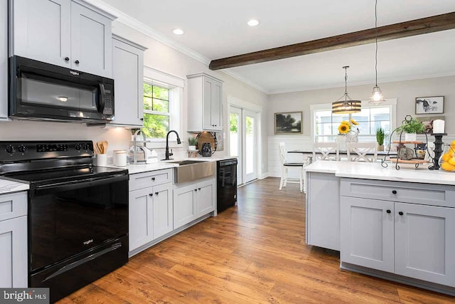 kitchen with light hardwood / wood-style floors, crown molding, hanging light fixtures, black appliances, and sink