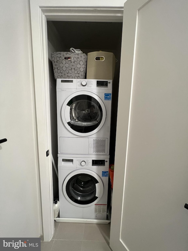 clothes washing area featuring light tile patterned floors and stacked washer / dryer