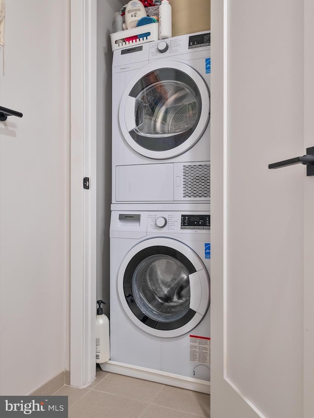 clothes washing area with stacked washer / dryer and light tile patterned floors