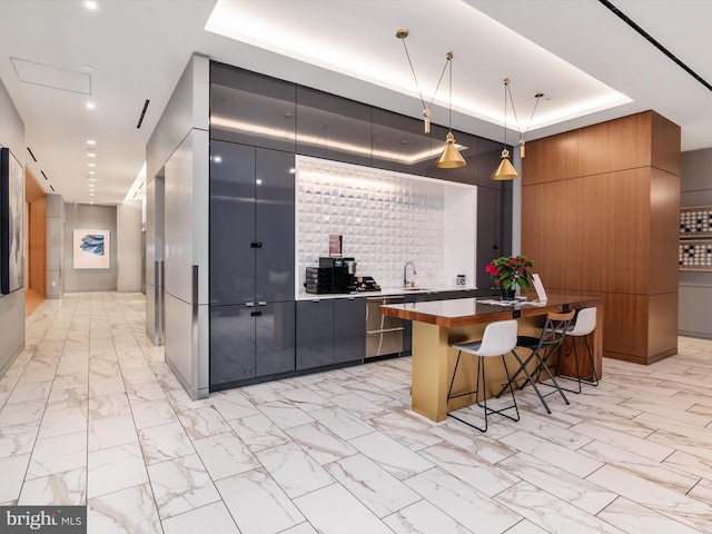 kitchen with a kitchen breakfast bar, a tray ceiling, a spacious island, pendant lighting, and dishwasher