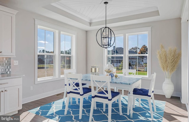 dining space featuring dark hardwood / wood-style floors, plenty of natural light, a raised ceiling, and a notable chandelier