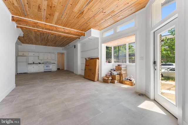 unfurnished living room with a healthy amount of sunlight, wooden ceiling, and light tile floors