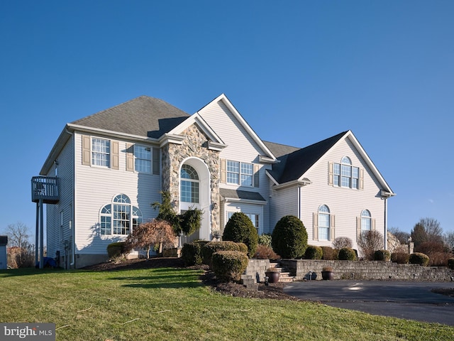 view of front property with a balcony and a front lawn