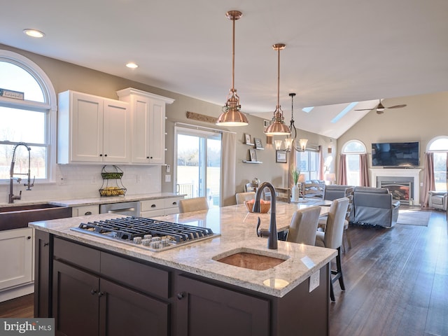 kitchen featuring dark wood-type flooring, ceiling fan with notable chandelier, white cabinets, decorative light fixtures, and backsplash