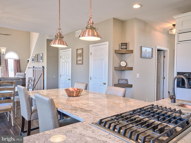 kitchen featuring white cabinetry, a kitchen breakfast bar, dark hardwood / wood-style floors, light stone counters, and decorative light fixtures