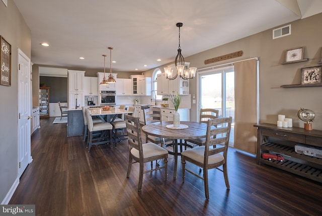 dining space with sink, dark hardwood / wood-style floors, and an inviting chandelier