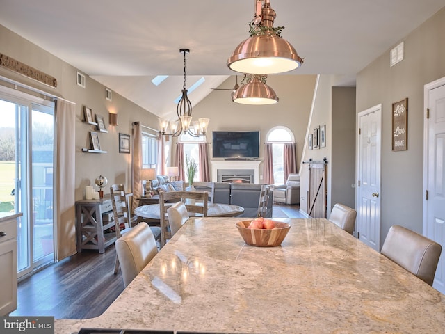 dining room with dark hardwood / wood-style floors, a healthy amount of sunlight, and lofted ceiling