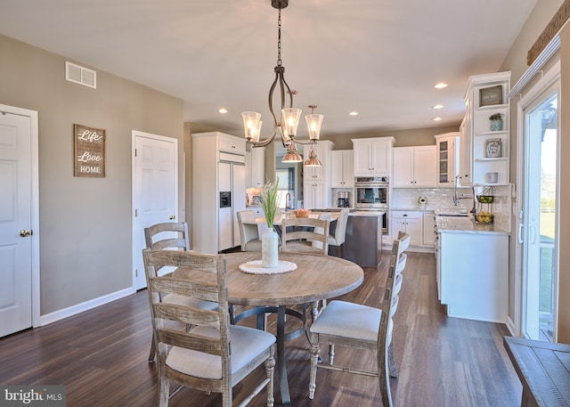 dining space featuring dark hardwood / wood-style floors, sink, and an inviting chandelier